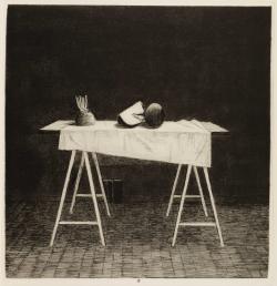 Mustavalkoinen asetelma, jossa pukkijaökaisella pöydällä valkoinen pöytäliina ja vihanneksia. 